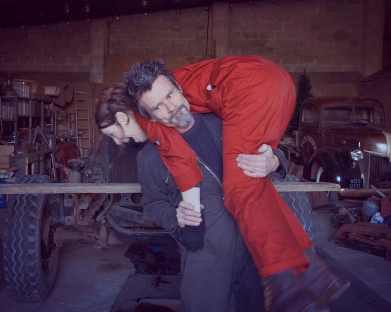 Man lifting a woman in red overalls over his shoulder