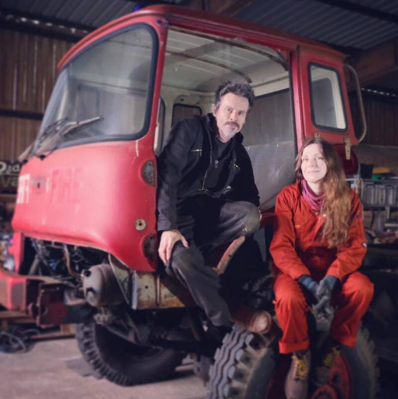 Man and woman in a workshop sitting in the doorway of an old Bedford truck