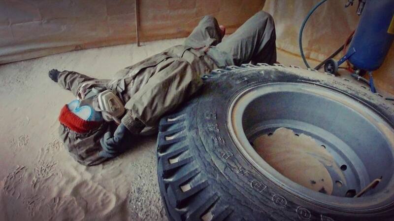 Woman in protective clothing lying next to a truck tyre