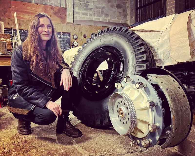 Woman crouching next to a truck wheel