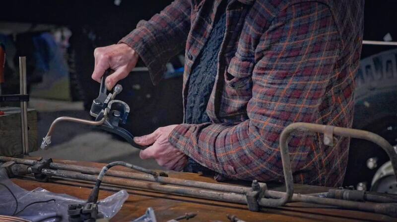 Man using a pipe bender to fabricate metal brake lines
