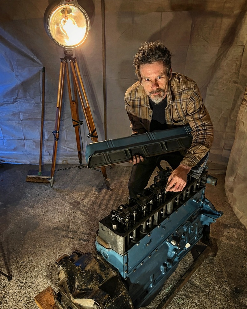 Man inspecting a big petrol engine from an old Bedford truck