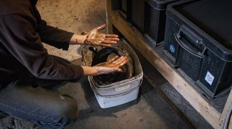 Man’s greasy hands in a bucket cleaning car parts