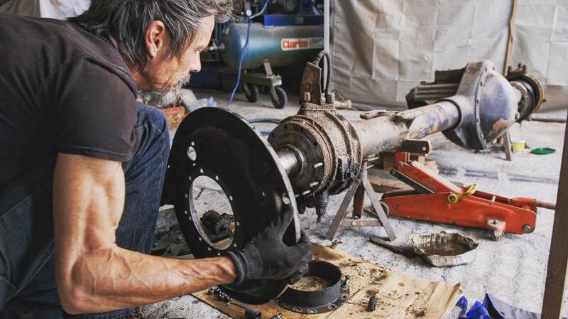 Man dismantling the front axle of a Bedford truck