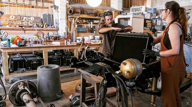 Man and woman fitting a radiator to the bare chassis of a newly restored 1970s Bedford truck
