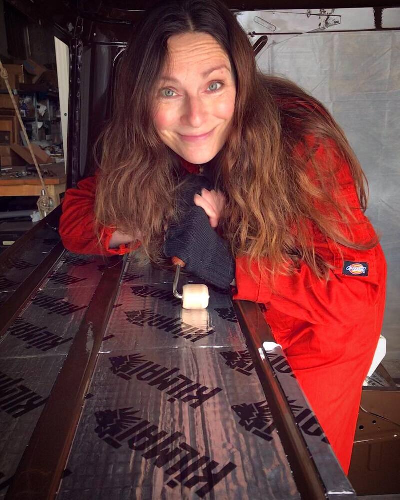 Woman in orange overalls soundproofing a Bedford truck cab