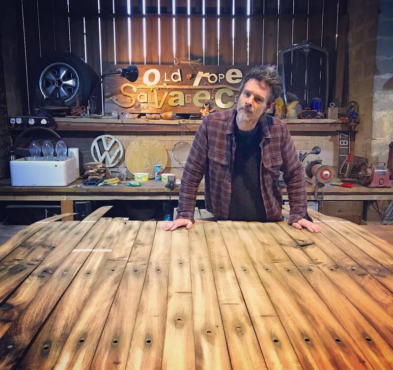 Man in workshop standing at a workbench with slices of oak wood laid out in front of him