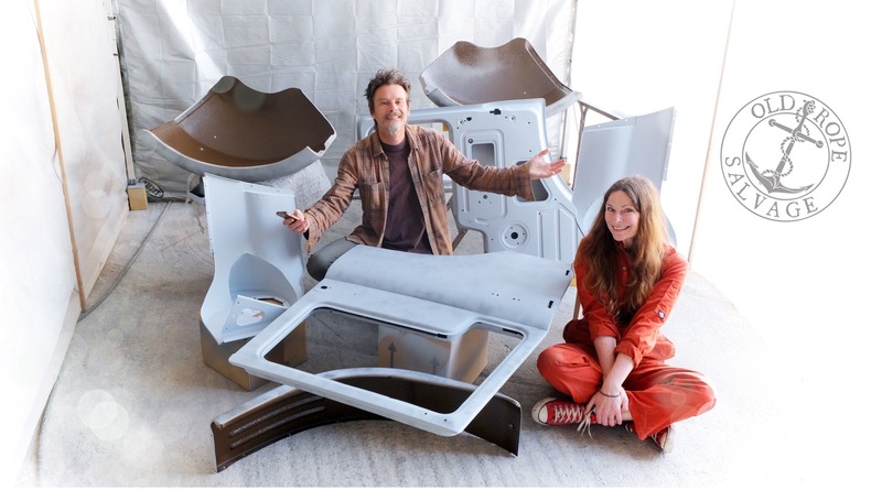 Man and woman sitting in a paint spray Booth with Bedford truck panels in grey primer