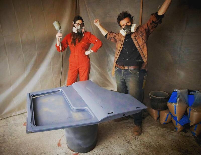 Man and woman in a paint booth about to spray paint a Bedford truck door