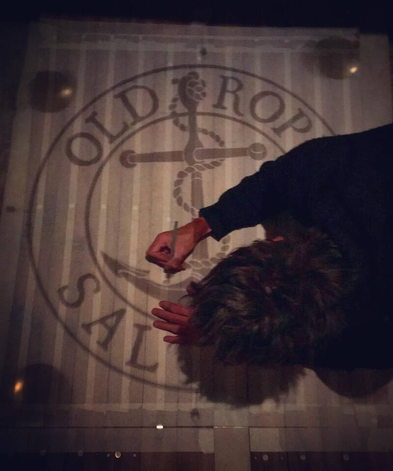 Man drawing old rope salvage logo on to wooden boards