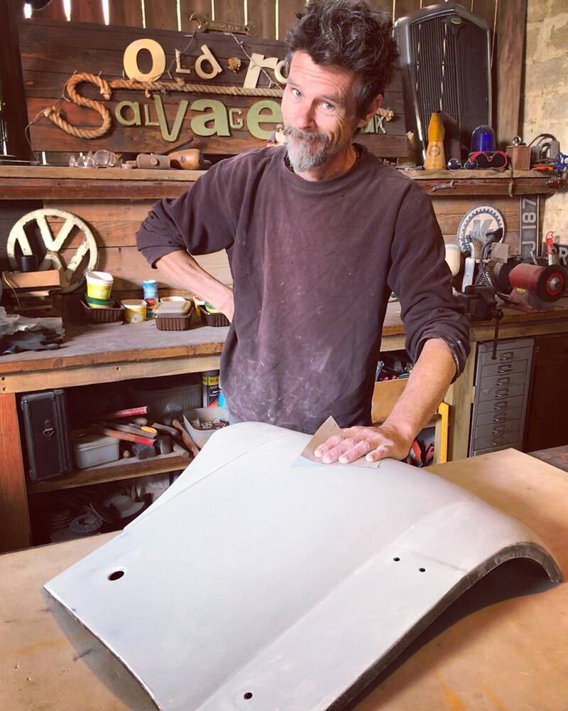 Man standing at workbench sanding a car panel