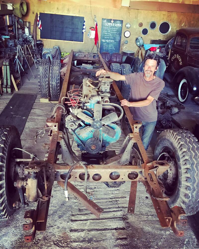 Man standing next to a vintage Bedford truck chassis