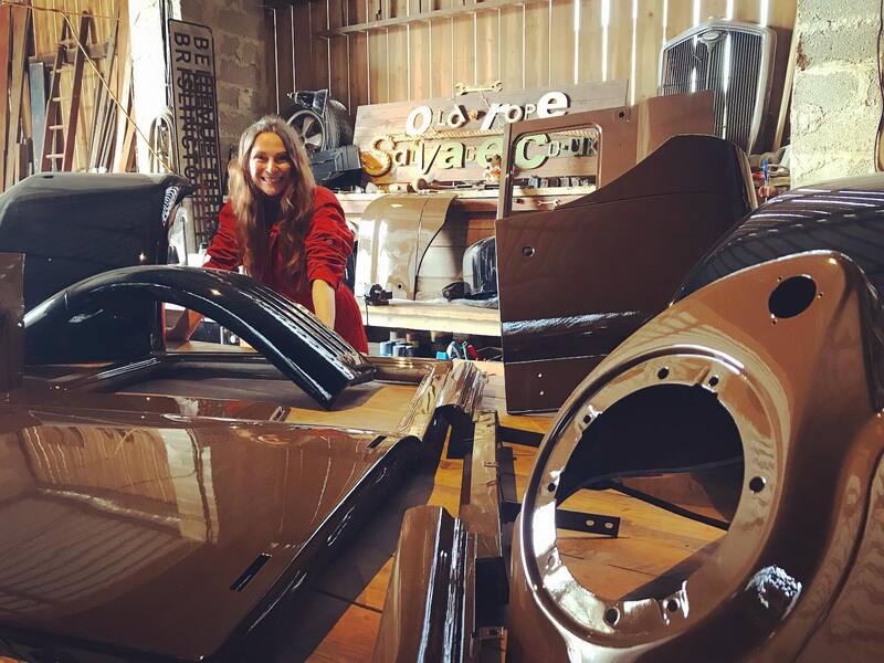 Woman in orange overalls standing at a bench filled with Bedford truck panels