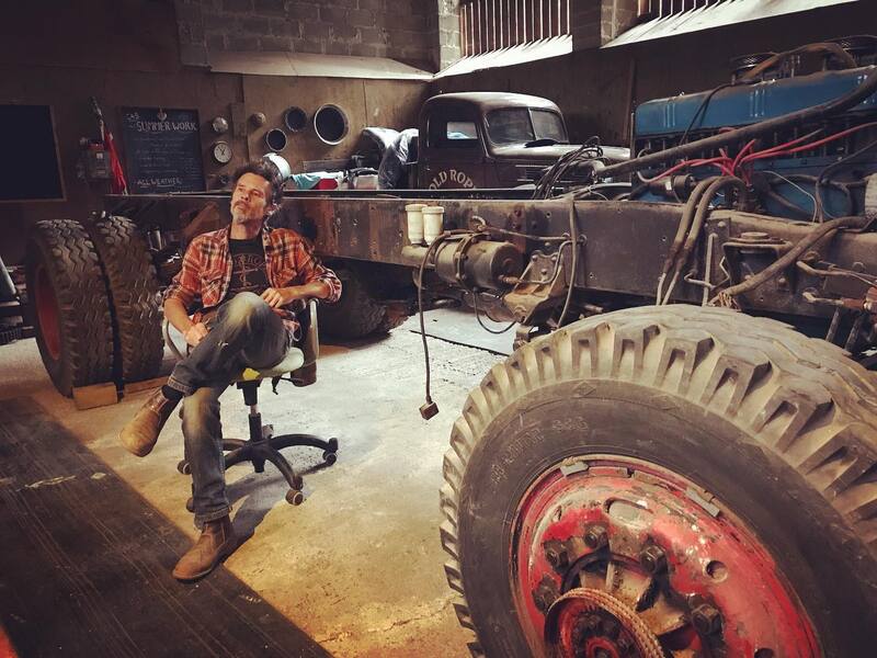 Man sitting in front of an old Bedford truck chassis