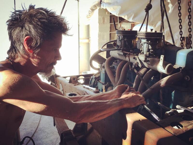 Man in a workshop inspecting a big 6 cylinder engine 