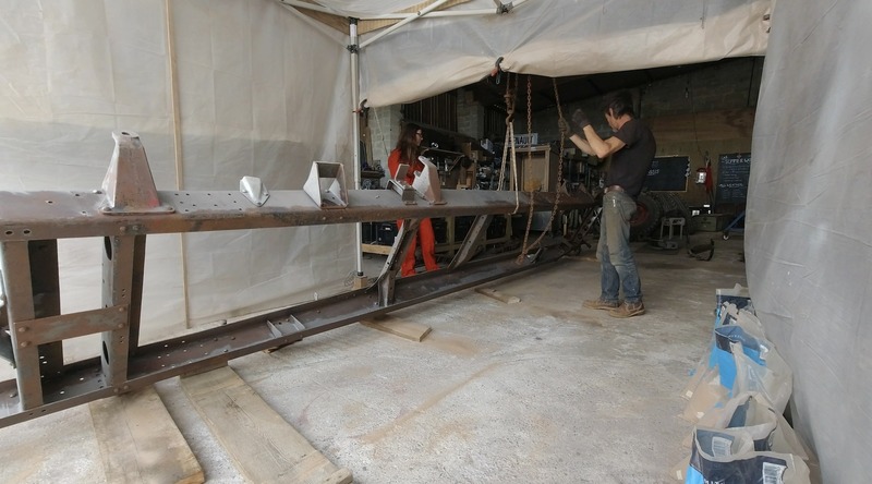 Man and woman moving a chassis frame around a workshop