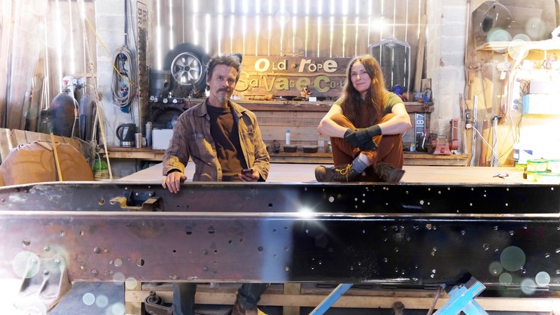 Man and woman with a half painted truck chassis frame