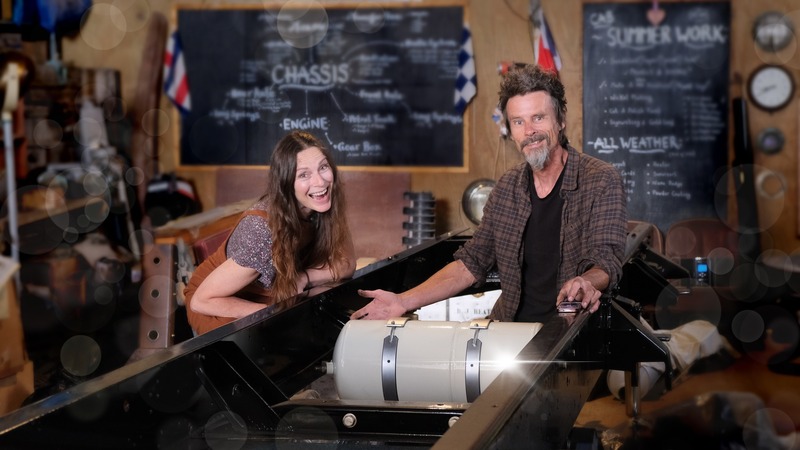 Man and woman smiling with an air tank and a Bedford truck chassis frame