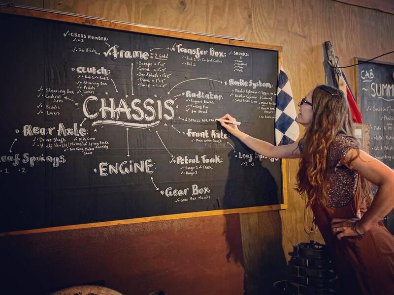 Woman standing at a chalk board writing out the parts of a truck