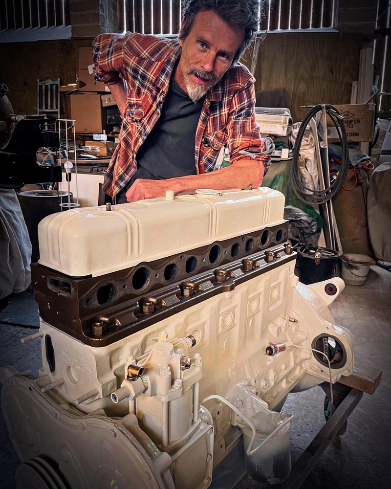 Man with a freshly restored and white painted petrol Bedford truck engine