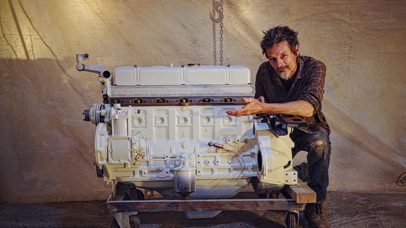 Man with a freshly white painted truck engine