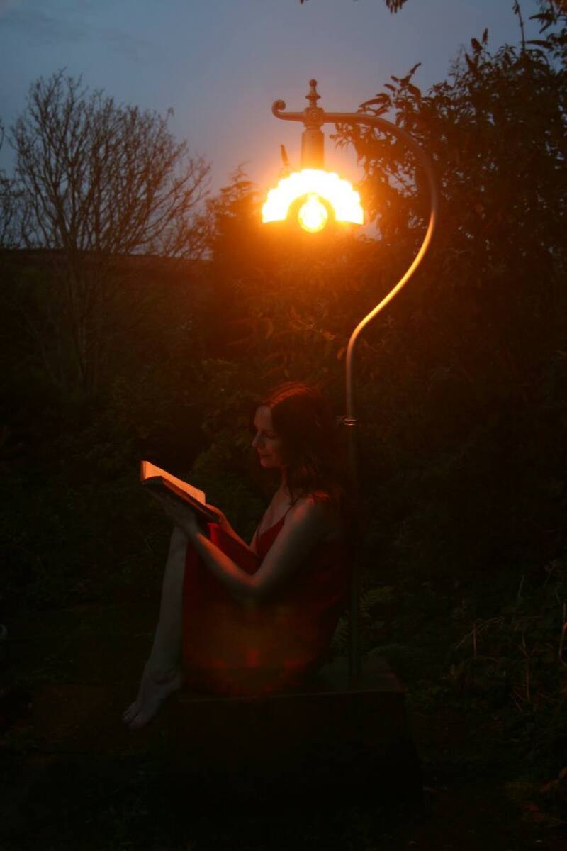 Woman reading under an old style street lamp