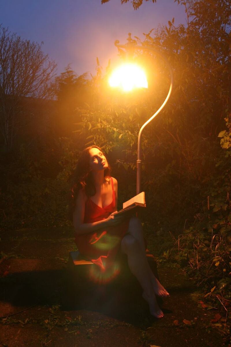 Woman sits under an old street lamp reading