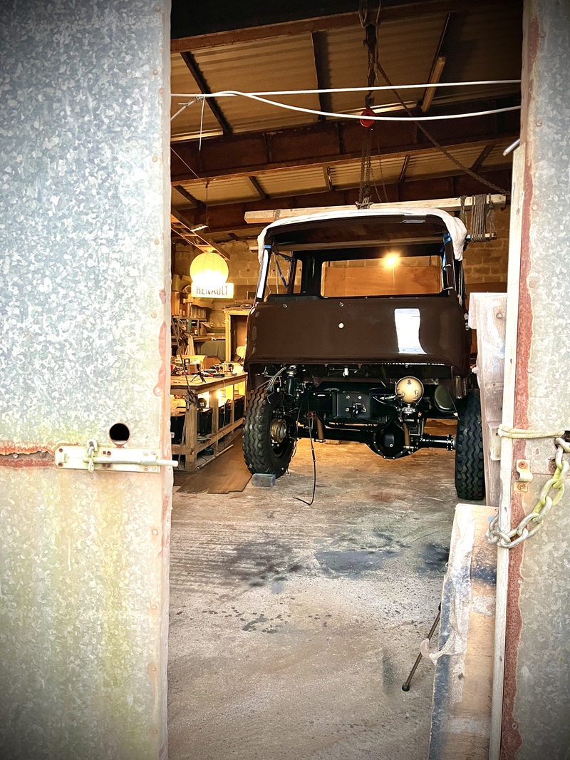 Partly dismantled newly restored brown Bedford truck viewed through the metal doors in to a workshop