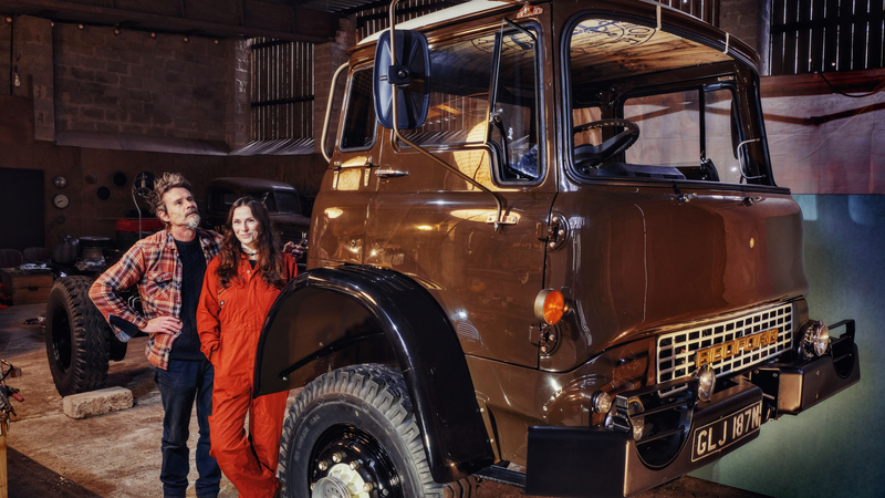 Man and woman standing next to a newly restored Bedford truck painted brown and black