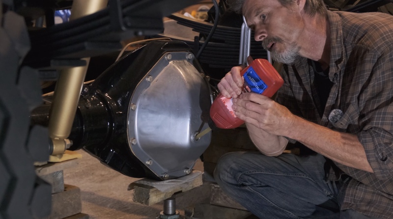 Man putting oil in to the front axle of a Bedford truck