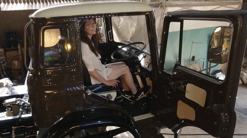 Woman in shorts sitting in the drivers seat of a classic Bedford truck