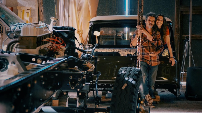 Man and woman stand with a 1970s Bedford truck in the process of being restored