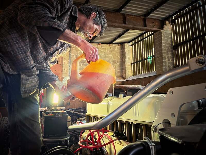 Man filling a Bedford truck petrol engine with oil