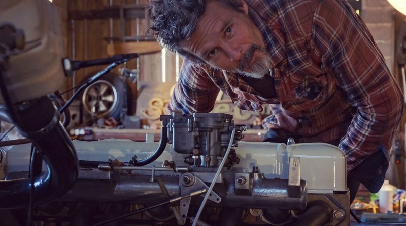Man leaning over the petrol engine in a Bedford truck