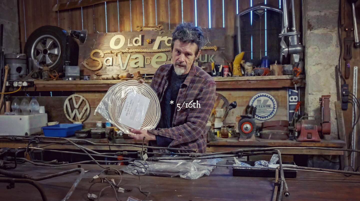 Man in workshop holding a roll of metal pipe