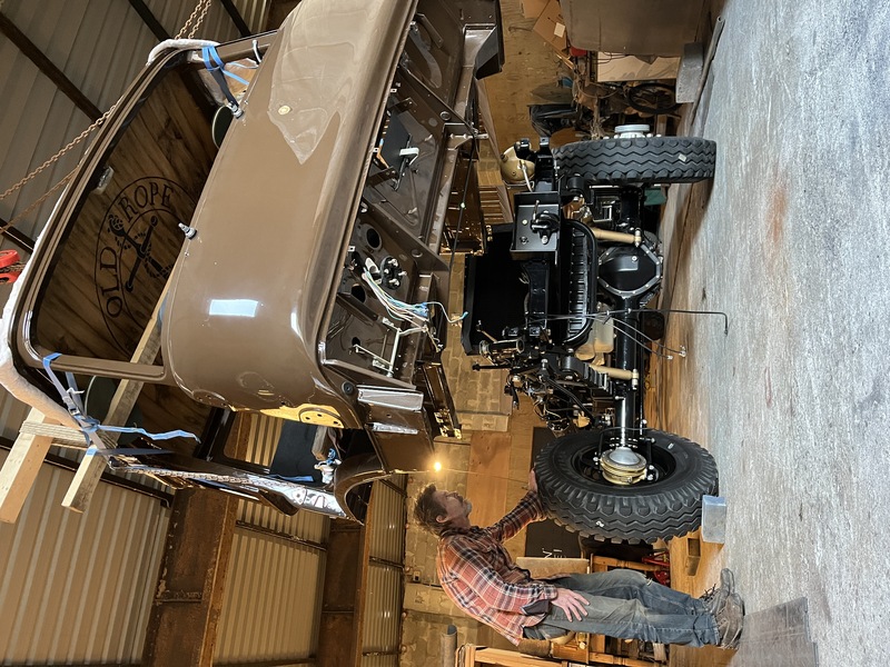 Man with a classic restored Bedford truck with cab getting winched on to the chassis