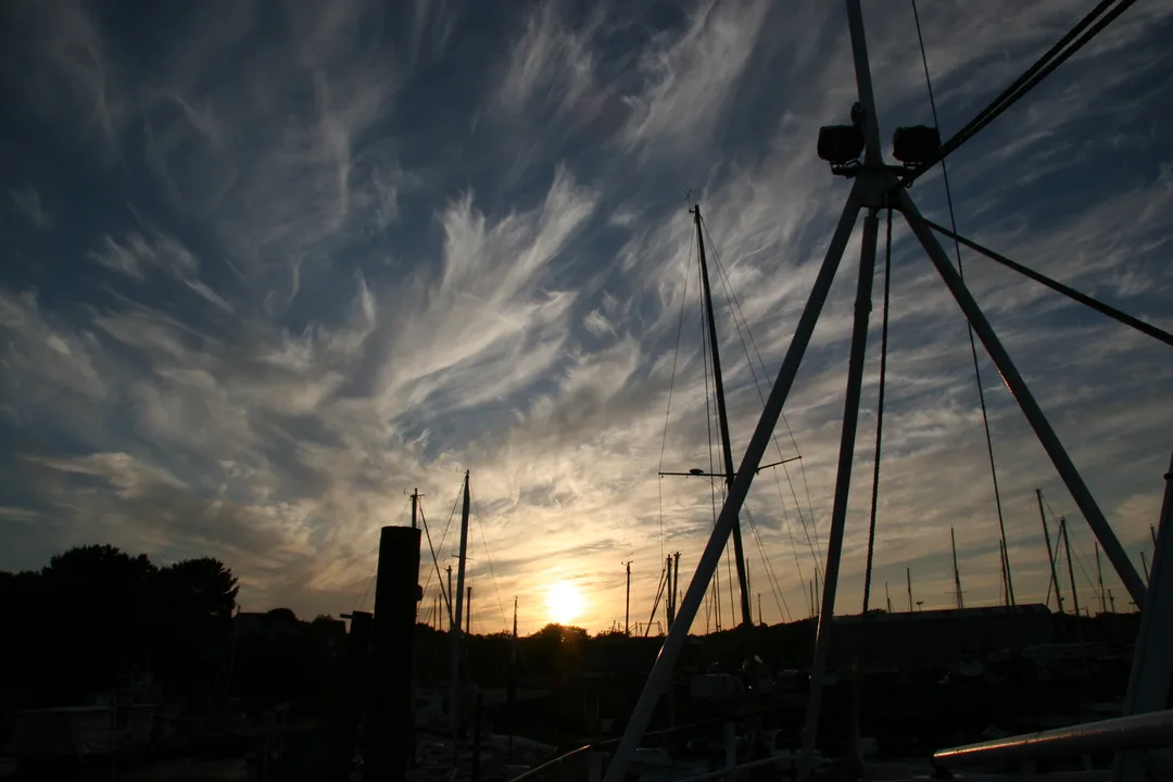 Sunrise over the silhouettes of boat masts in a boat yard