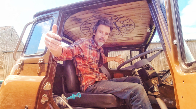 Man in a check shirt sitting in the drivers seat of a Bedford truck